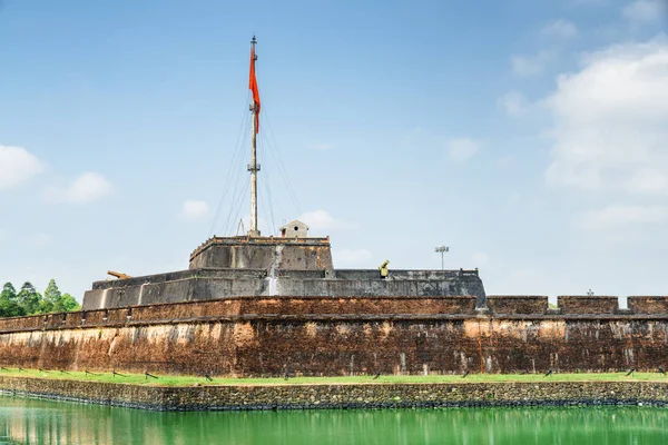 View of the Flag Tower of the Citadel on blue sky background in Hue, Vietnam. Fortress wall and moat surrounding the Imperial City with the Purple Forbidden City. Hue is a popular tourist destination.