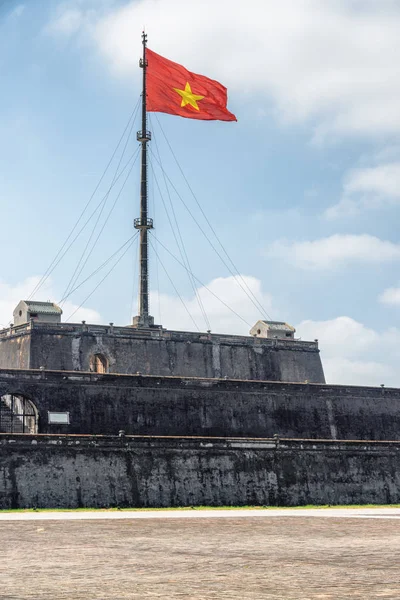 Beautiful view of the flag of Vietnam (red flag with a gold star) fluttering over a tower of the Citadel on blue sky background in Hue, Vietnam. Within the Citadel is the Imperial City.