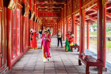 Hue, Vietnam - 4 Nisan 2018: Renkli geleneksel giysiler Ao dai kırmızı ahşap koridor içinde mor Yasak Şehir kalenin içinde imparatorluk şehri, Vietnamca kadınlarda.