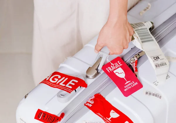 越南芽庄市 2016年8月16日 在凸轮金兰湾机场手拿手提箱的人 亮红色行李标签 小心轻放 附着在白色塑料手提箱上 — 图库照片