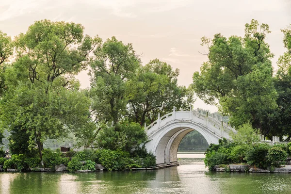 Guilin park Çin yeşil ağaçların arasında göl kenarında beyaz ikiz mermer köprü görünümünü akşam. Doğal yaz manzara. Guilin Asya'nın popüler bir turistik yer.