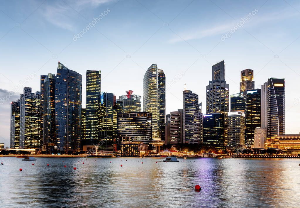 Scenic evening view of Marina Bay and downtown of Singapore. Skyscrapers and other modern buildings are visible on blue sky background. Singapore is a popular tourist destination of Asia.