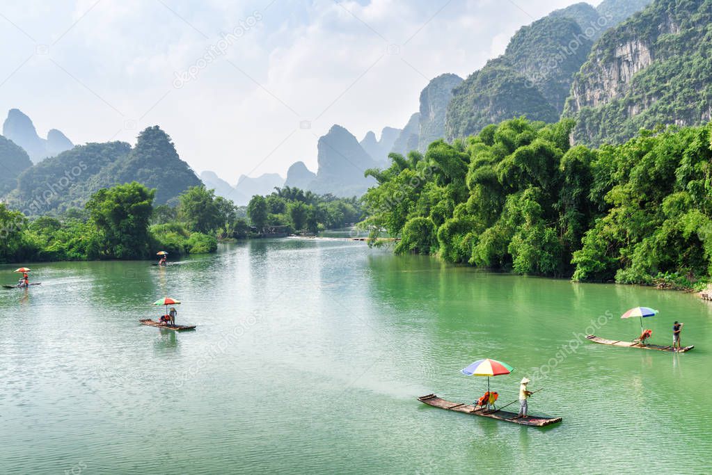 Amazing view of small tourist bamboo rafts sailing along the Yulong River among green woods and karst mountains at Yangshuo County of Guilin, China. Yangshuo is a popular tourist destination of Asia.