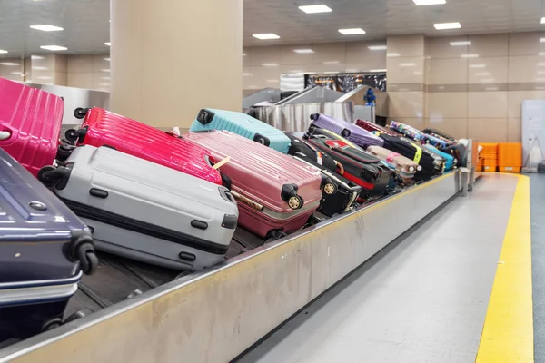 空港の旅客ターミナルの到着エリアで荷物コンベヤー ベルトに明るいピンクのスーツケース 手荷物カルーセル — ストック写真