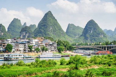 Yangshuo Town, köprü ve doğal Karstik dağlar mavi gökyüzü arka plan üzerinde inanılmaz güzel manzara. Muhteşem güneşli manzara. Turist tekneleri Li Nehri üzerinde (Lijiang), Guilin, Çin görülebilir.