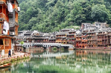 Güzel manzaralı Phoenix antik kenti (Fenghuang) doğal yeşil ağaçların arasında Tuojiang nehir (Tuo Jiang Nehri) köprüden. Su, Çin geleneksel Çin nehir binalar yansıyan.