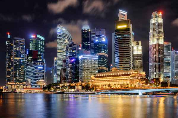 Night view of skyscrapers and old colonial building by Marina Bay at downtown of Singapore. Colorful city lights reflected in water of the bay. Singapore is a popular tourist destination of Asia.