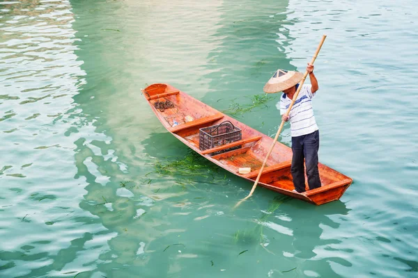 Barquero asiático en sombrero de bambú tradicional en barco de madera —  Fotos de Stock