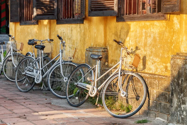 Rowery zaparkowane na żółtym ścianie starego domu. Hội an — Zdjęcie stockowe