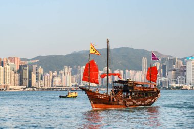 Hong Kong - 21 Ekim 2017: Victoria Limanı 'nda kırmızı yelkenli geleneksel Çin ahşap yelkenli gemisinin muhteşem manzarası. Hong Kong Adası 'nda yüksek binalar görülebilir..