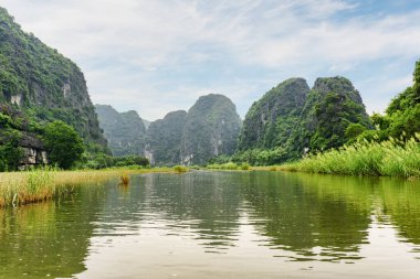 Tam Coc, Ninh Binh Eyaleti, Vietnam 'daki Ngo Dong Nehri' nin sularına yansıyan doğal karst kulelerinin muhteşem manzarası. Tam Coc Asya 'da popüler bir turistik merkezdir..