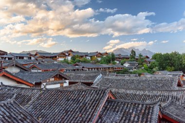 Çin 'in Lijiang şehrindeki otantik evlerin geleneksel Çin siyah kiremit çatıları. Yeşim Ejder Dağı gün batımında görülebilir. Lijiang Asya 'nın popüler bir turizm merkezidir..