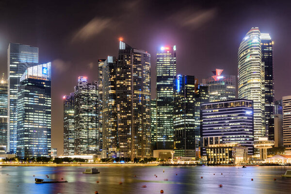 Awesome night view of downtown in Singapore. Amazing skyscrapers and other modern buildings on dark sky background. Colorful city lights reflected in water of Marina Bay. Beautiful cityscape.
