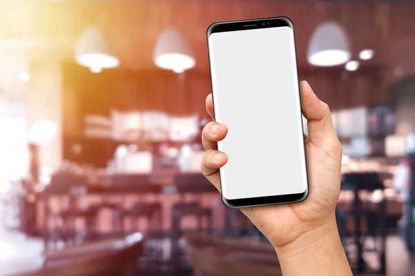 コーヒー ショップぼやけて背景と現代のスマート フォンを持っている手 — ストック写真