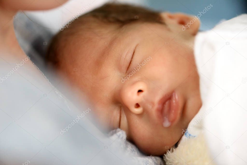 Newborn baby boy with milk drop in his mouth