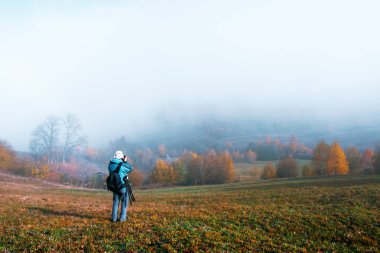 Fotoğrafçı, sonbahar manzarasının fotoğrafını çekiyor.