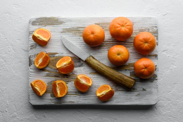 Mandarijnen en mes op houten plank — Stockfoto