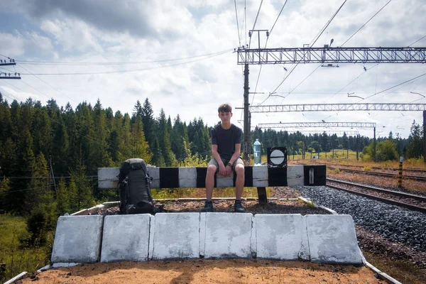 Nastolatek na dworzec kolejowy siedzi z baclpack — Zdjęcie stockowe
