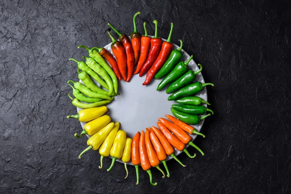 Different colors hot peppers in wooden plate — Stock Photo, Image
