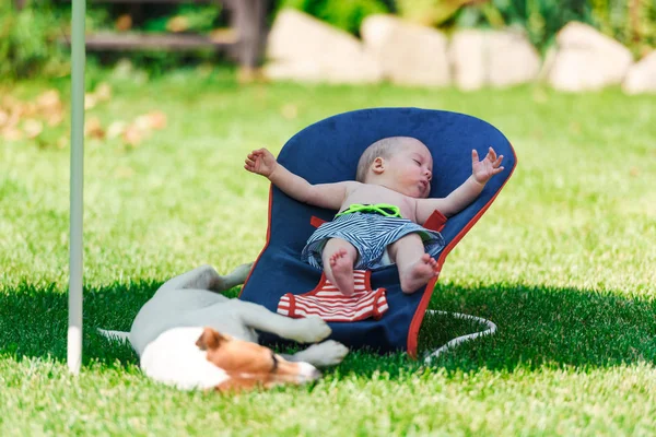 Baby pojke ligger på en solstol på grön gräsmatta — Stockfoto
