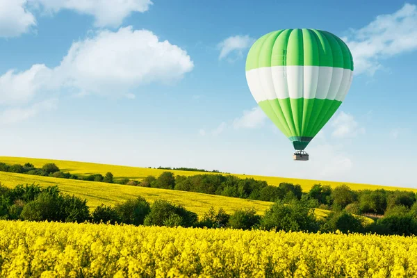 Green balloon under yellow rape field — Stock Photo, Image