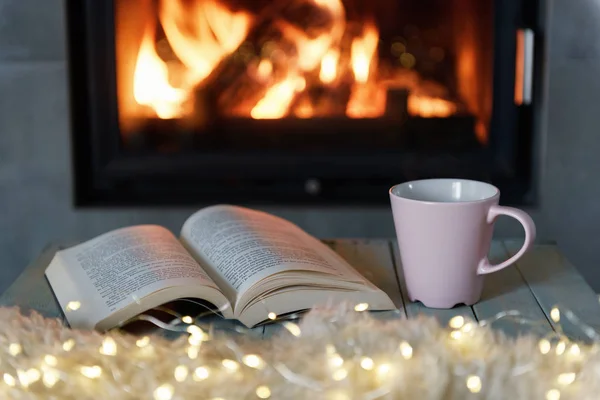 Libro y taza de té cerca de la chimenea — Foto de Stock