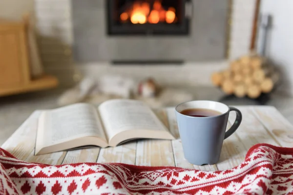 Libro y taza de té cerca de la chimenea — Foto de Stock