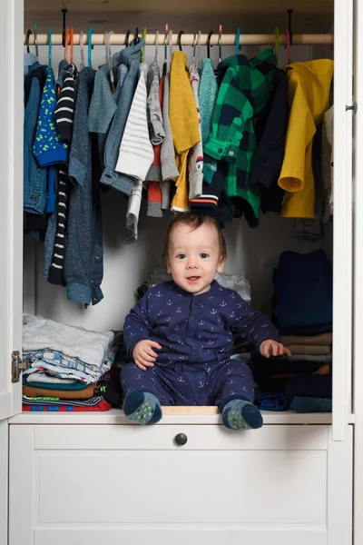 Smiling kid hiden in clothing closet — Stockfoto