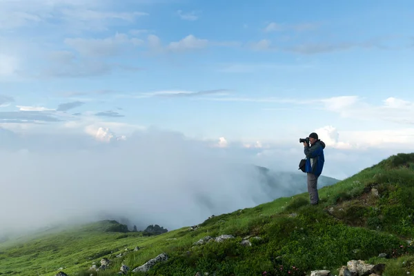 Photographer taking photo of cloudy mountains — Stock Photo, Image