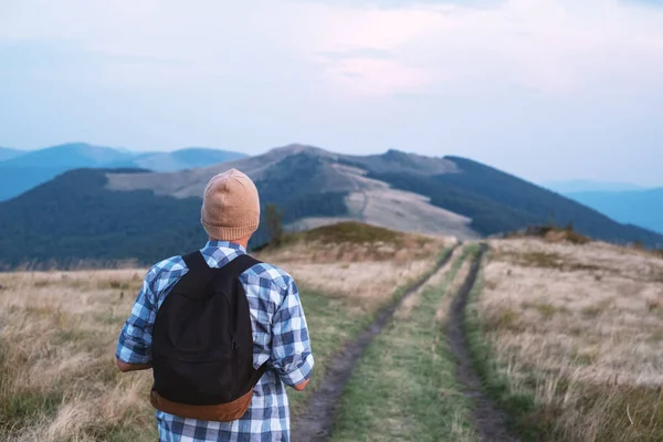 Homem com mochila na estrada das montanhas — Fotografia de Stock