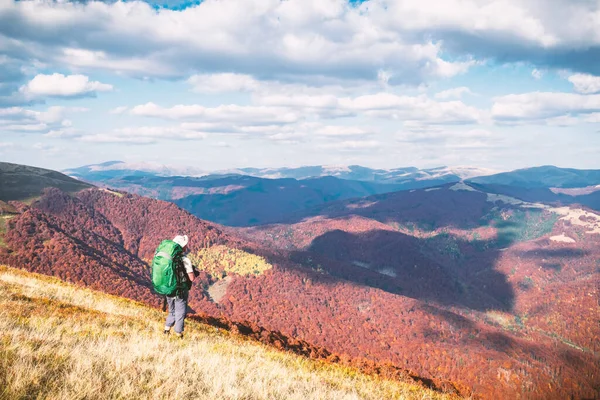 Backpacker na słonecznej jesiennej łące z pomarańczowymi bukami — Zdjęcie stockowe