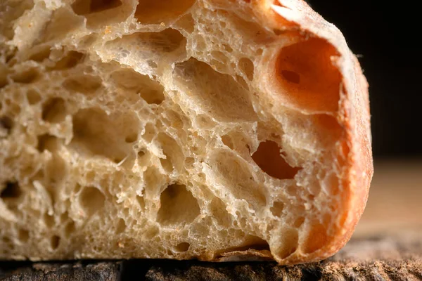 Köy tahtasında gözenekli ekmek kırıntısı ve çıtır çıtır deri. Makro ekşi somun dokusu.