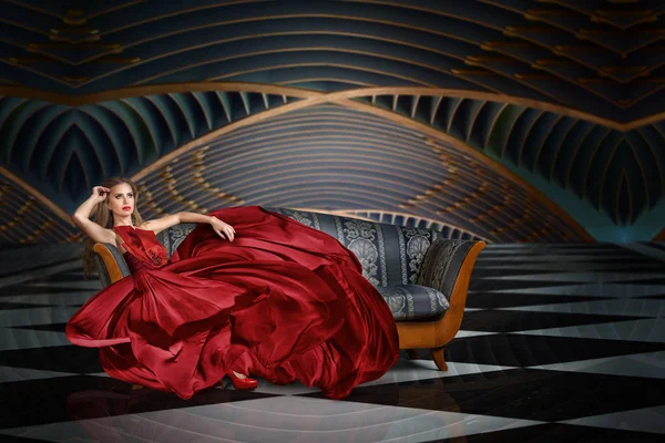 長いドレスを着てソファーに座っている美しい女性のファッション ポートレート — ストック写真