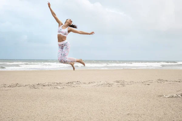 海の砂浜でジャンプ若いスリムな幸せな女 — ストック写真