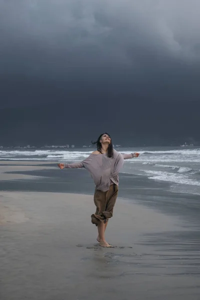 重い暗い雲の前で雨の日に嵐の海を歩いて若い女性 — ストック写真