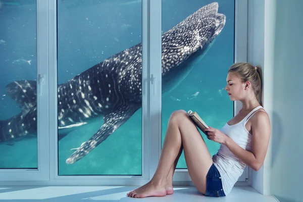 Jeune femme imaginant la vie sous-marine tout en lisant — Photo