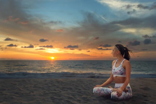 Junge schöne Frau entspannt sich in Yoga-Lotusposition auf Meeressand — Stockfoto