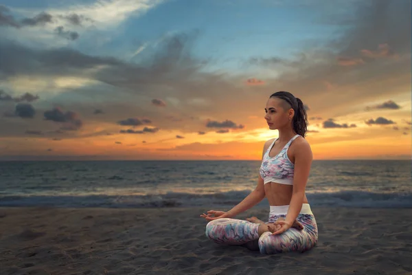 Молодая красивая женщина расслабляется в йоге Lotus позиции на морском песке — стоковое фото