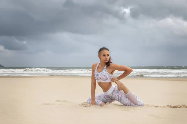 Молодая красивая женщина практикует йогу на песке — стоковое фото