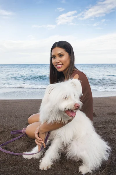 Güneşli bir günde deniz sahilinde köpeğiyle oynayan genç bir kadın. — Stok fotoğraf