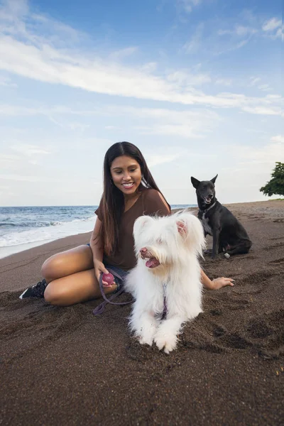 Güneşli bir günde deniz sahilinde köpeğiyle oynayan genç bir kadın. — Stok fotoğraf