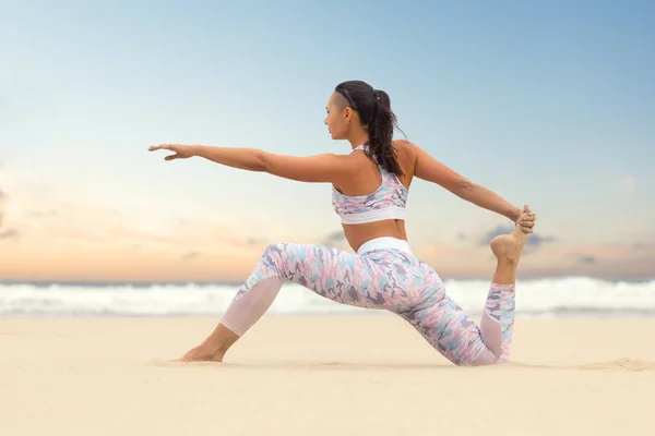 Genç ve güzel bir kadın deniz kumu üzerinde yoga yapıyor. — Stok fotoğraf