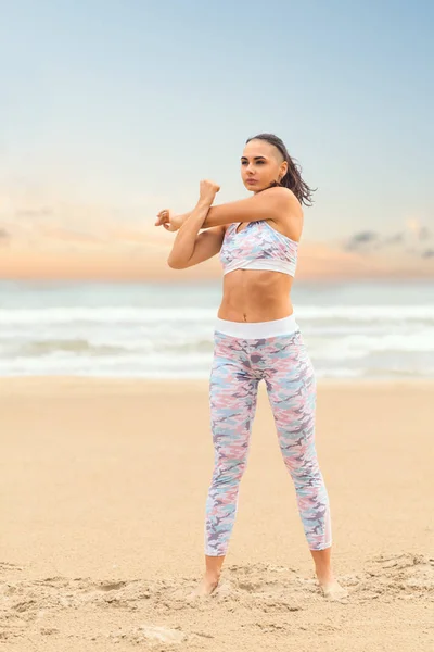 Genç ve güzel bir kadın deniz kumu üzerinde yoga yapıyor. — Stok fotoğraf