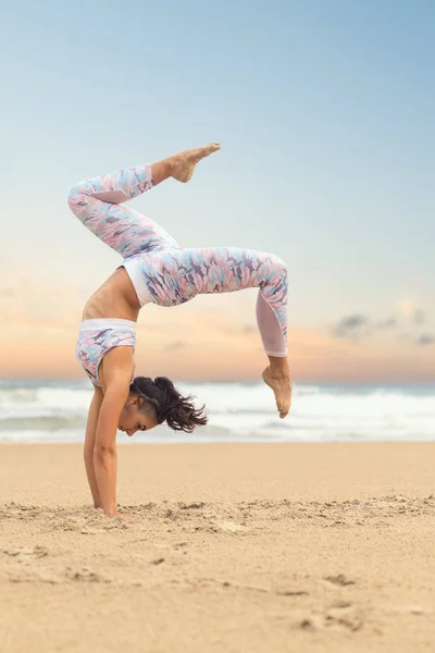 Genç ve güzel bir kadın deniz kumu üzerinde yoga yapıyor. — Stok fotoğraf