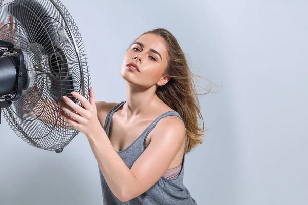 Mujer joven disfrutando del viento fresco de ventilador eléctrico — Foto de Stock