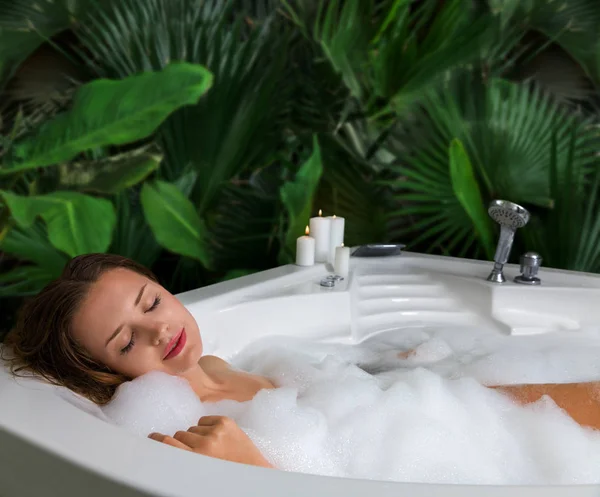 Une femme se détend dans un bain à remous avec de la mousse de savon — Photo