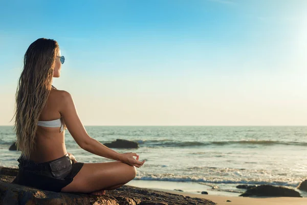 Mooie jonge vrouw zitten op het strand — Stockfoto