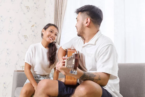 Przystojny młody Asian Mężczyzna gra akustyczna gitara i śpiew dla jego piękny przyjaciółka — Zdjęcie stockowe