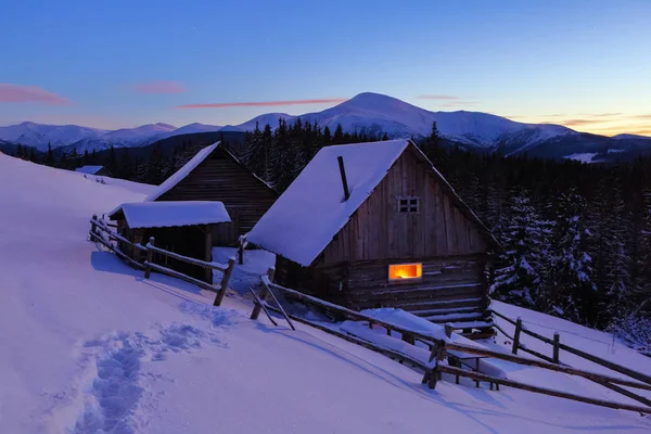 一条践踏的小路通向白雪覆盖的美丽雪山背景下的木屋 梦幻般的冬季风光 — 图库照片