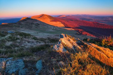 Dağları manzaraları. Güzel renkli gökyüzü ile gündoğumu toplayan. Çim gri taşlarla. Sıcak güneşli gün. 